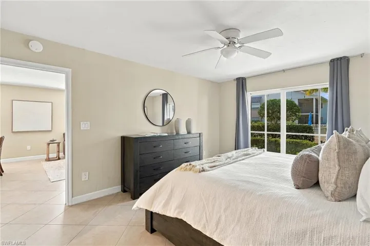 Neutral-toned walls, tile flooring, large multi-pane windows, and a ceiling fan with integrated lighting
