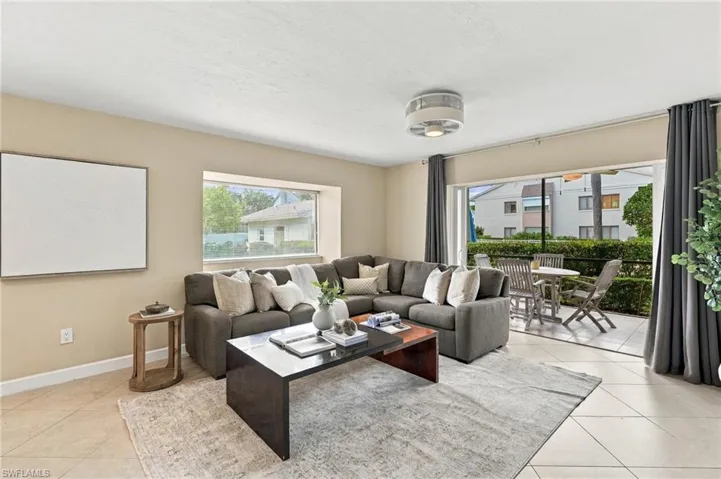 Living area featuring large-format tile flooring, recessed ceiling lighting, a recessed window nook, and sliding glass doors opening to a covered patio
