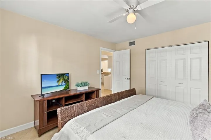 Interior space featuring neutral-toned walls, tile flooring, ceiling fan with integrated lighting, and dual-panel closet doors