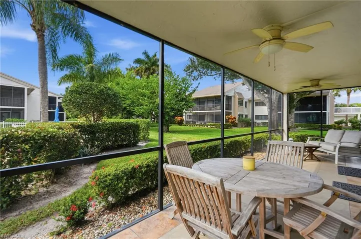 Screened lanai featuring tiled flooring and ceiling-mounted fans overlooking manicured lawn and landscaping