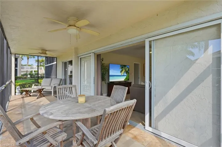 Screened-in patio featuring tiled flooring, dual ceiling fans, and large sliding glass doors