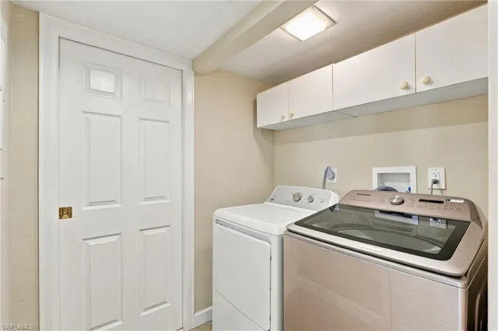 Laundry area featuring white built-in upper cabinetry, flush-mount overhead lighting, and a six-panel interior door