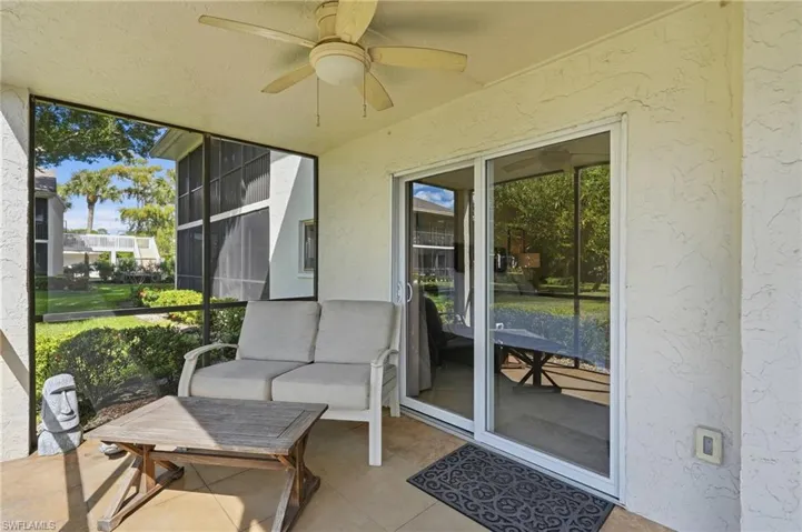 Screened-in lanai featuring tile flooring, a ceiling fan with integrated light, and sliding glass door access