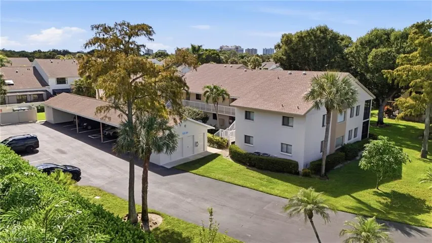Multi-story exterior featuring a shingled roof, stucco siding, and assigned covered parking