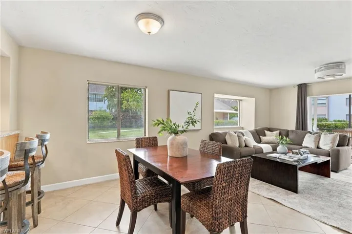 Open-concept interior featuring neutral wall tones, ceramic tile flooring, two ceiling-mounted light fixtures, and windows with natural lighting
