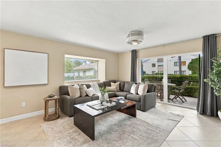Living area featuring large format tile flooring, a deep-set picture window, and glass sliding doors providing exterior access