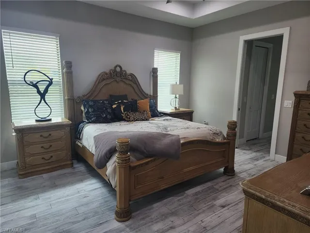Bedroom with wood look tile finished floors, 2 walk-in closets, and sliding door leading to the lanai