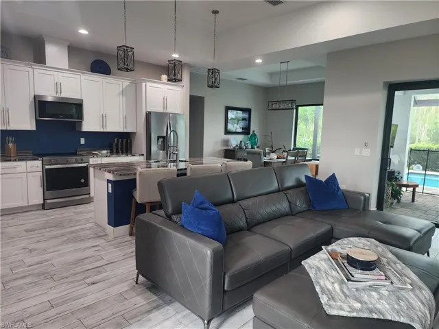 Living room with recessed lighting, light wood finished floors, and a tray ceiling