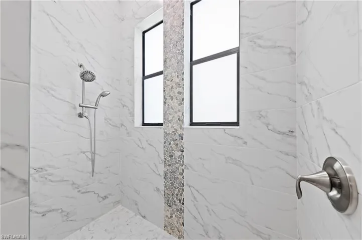 Bathroom featuring a marble finish shower and a dual water head