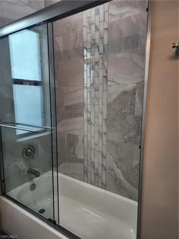 Full bath featuring combined bath / shower with glass door