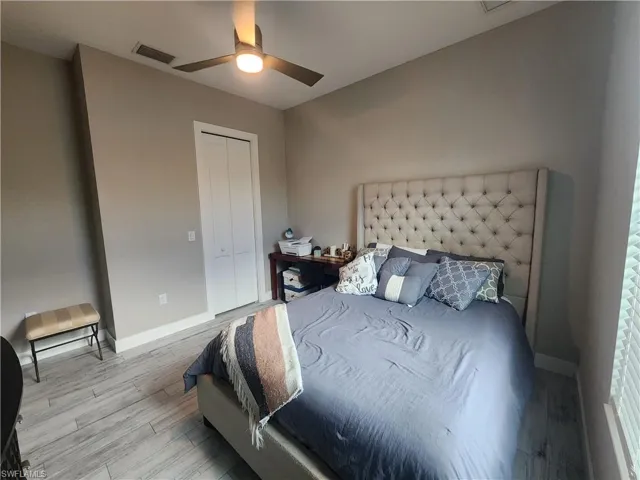 Bedroom featuring wood finished floors, a closet with wood shelving, and a ceiling fan