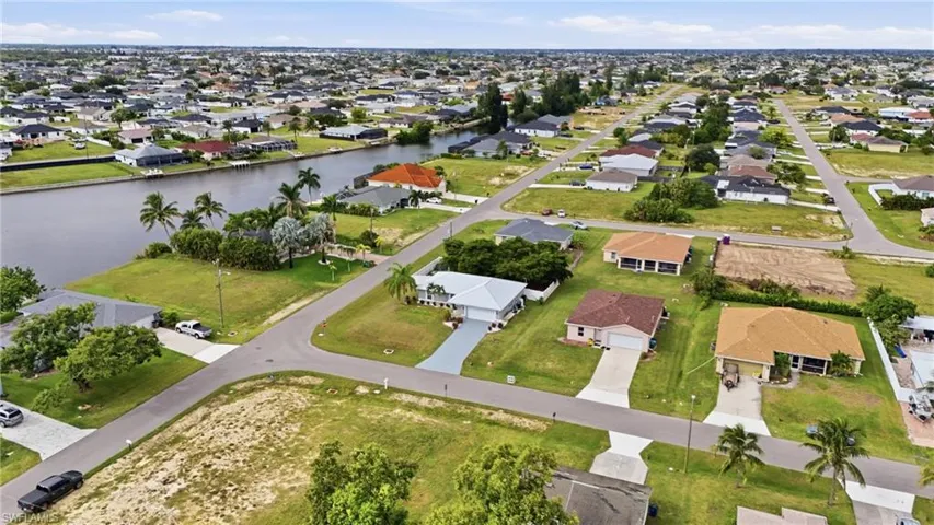 Aerial view of property and surrounding area featuring nearby suburban area and a large body of water