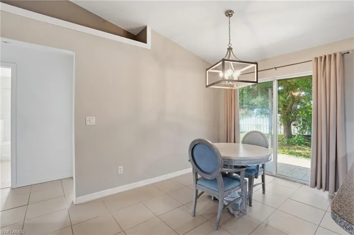 Dining room featuring light tile patterned floors, a chandelier, and lofted ceiling