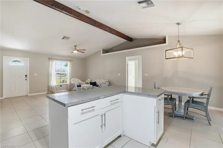 Kitchen featuring light tile patterned floors, white cabinets, pendant lighting, open floor plan, and light countertops