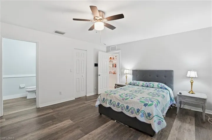 Bedroom with dark wood-style flooring, ensuite bathroom, and ceiling fan