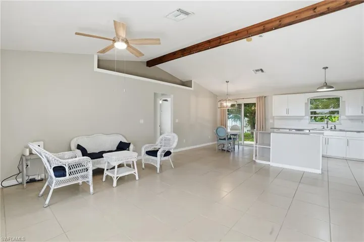 Sitting room featuring beamed ceiling, ceiling fan, light tile patterned floors, and high vaulted ceiling