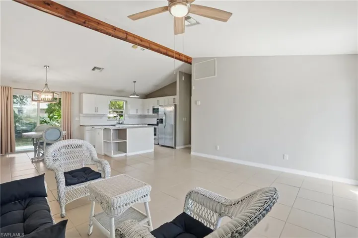 Living room featuring beamed ceiling, light tile patterned flooring, high vaulted ceiling, and a ceiling fan