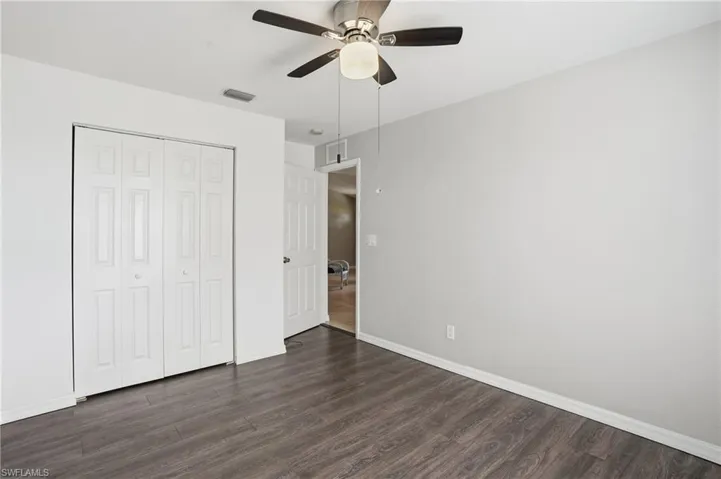 Unfurnished bedroom featuring dark wood-style flooring, a ceiling fan, and a closet