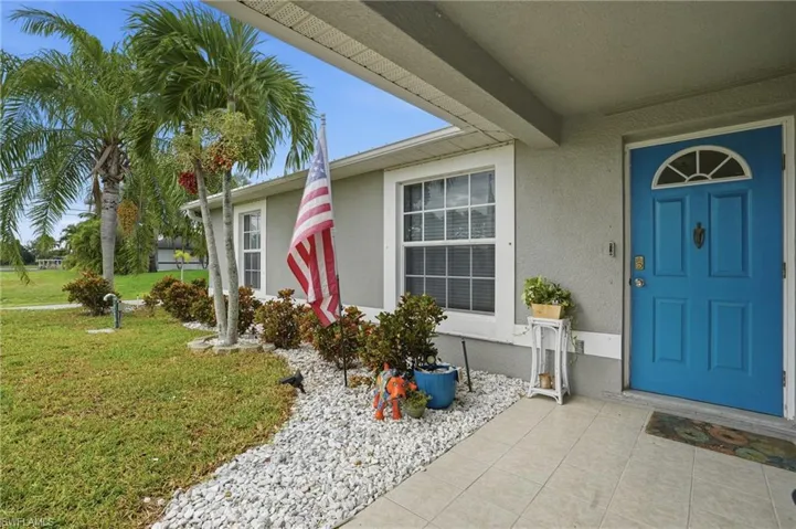 Doorway to property featuring a yard and stucco siding