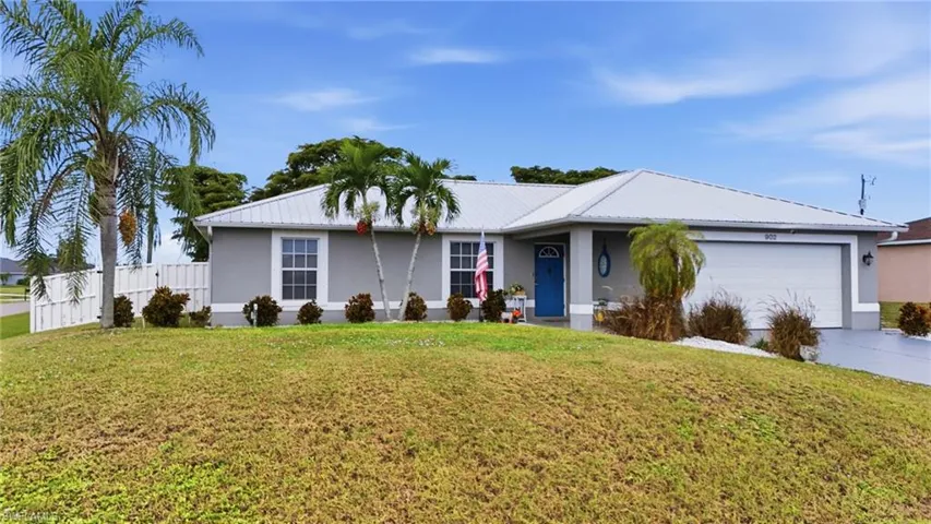 Ranch-style house featuring stucco siding, driveway, a garage, and a metal roof