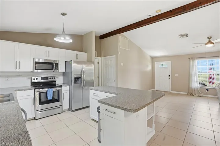 Kitchen featuring stainless steel appliances, hanging light fixtures, white cabinetry, open shelves, and a center island