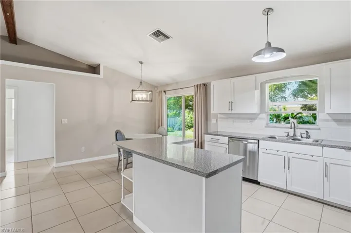 Kitchen with hanging light fixtures, white cabinets, open shelves, and light tile patterned floors