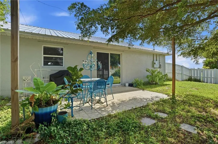 Rear view of house featuring stucco siding, a patio area, and a metal roof