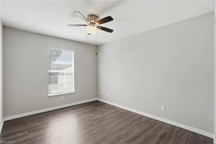 Empty room featuring dark wood finished floors and a ceiling fan