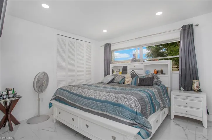 Recessed lighting, louvered bi-fold closet doors, large window, and white tile flooring