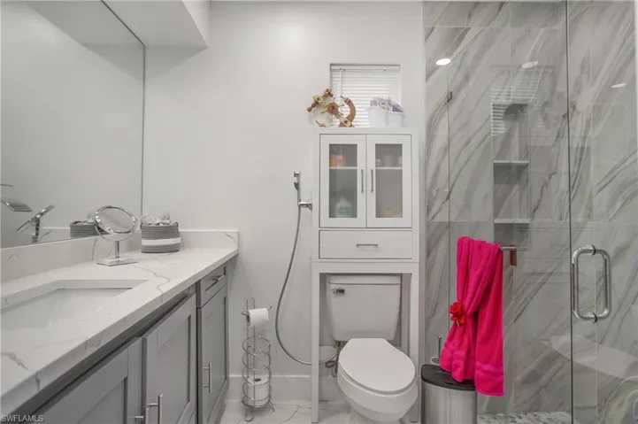 Vanity with a single undermount sink, a polished countertop, and gray shaker cabinetry