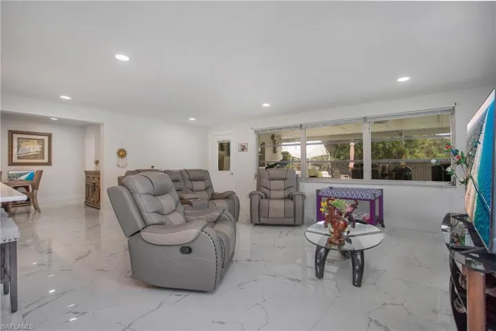 Recessed lighting illuminates the white walls and large format tile flooring throughout this open space