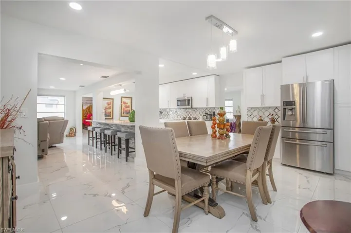 White cabinetry, stainless steel appliances, recessed lighting, and a patterned tile backsplash