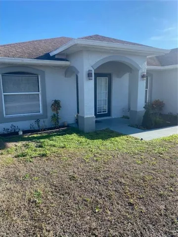 View of front of home with stucco siding and a front yard
