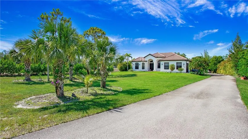 Mediterranean / spanish-style house with a front lawn, a tiled roof, stucco siding, and driveway