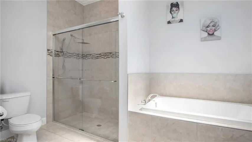 Bathroom with a stall shower, toilet, a bath, and tile patterned flooring