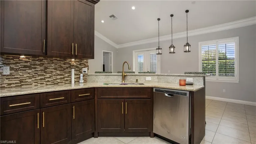 Kitchen featuring stainless steel dishwasher, a sink, a peninsula, tasteful backsplash, and ornamental molding