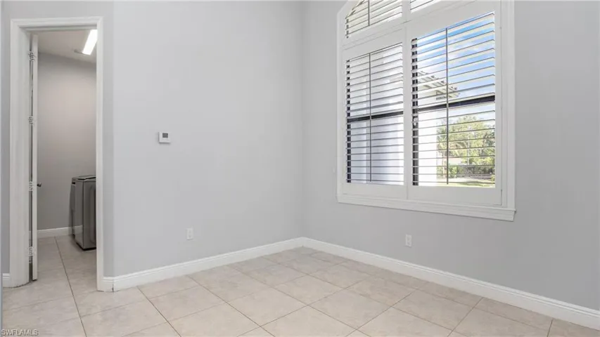 Empty room with light tile patterned flooring and baseboards
