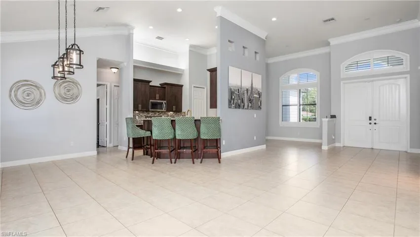 Entryway with light tile patterned floors, crown molding, baseboards, a high ceiling, and recessed lighting