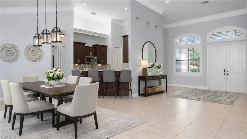 Virtually Staged  Dining room with a high ceiling, crown molding, and light tile patterned flooring