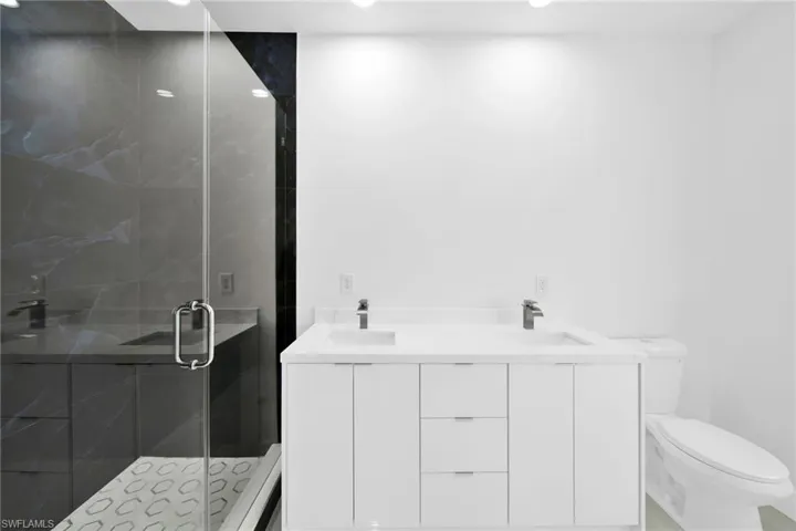 Bathroom featuring a shower with door and toilet