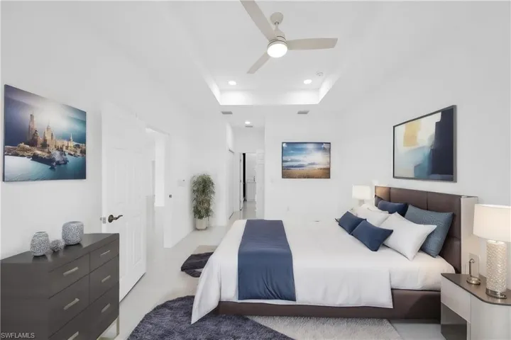 Bedroom with a tray ceiling, light carpet, and ceiling fan