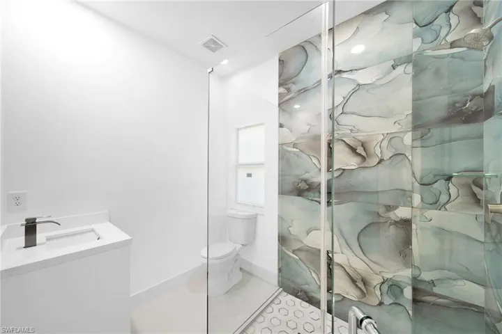 Bathroom with tile patterned floors, toilet, vanity, and an enclosed shower