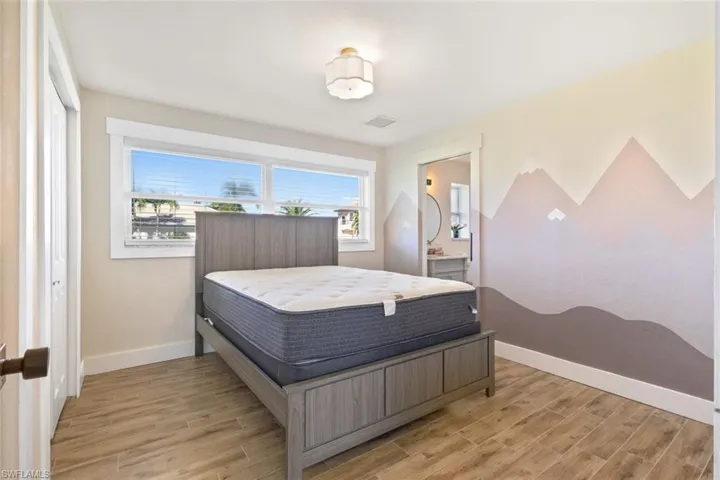 Bedroom featuring light wood-style flooring and ensuite bath
