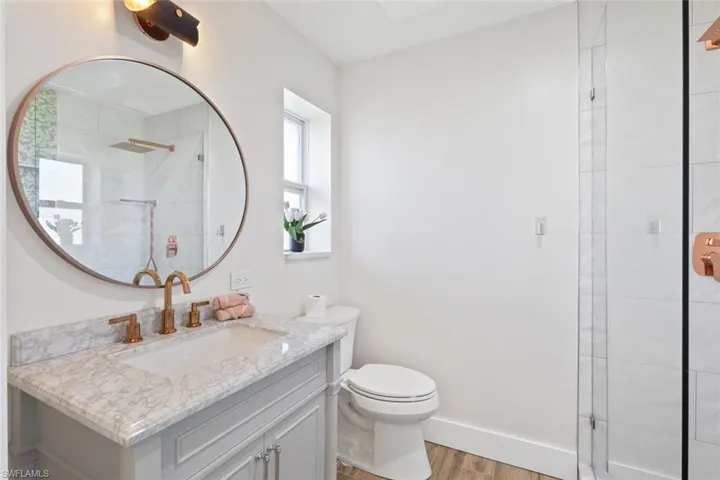 Full bathroom featuring vanity, wood finished floors, and a tile shower