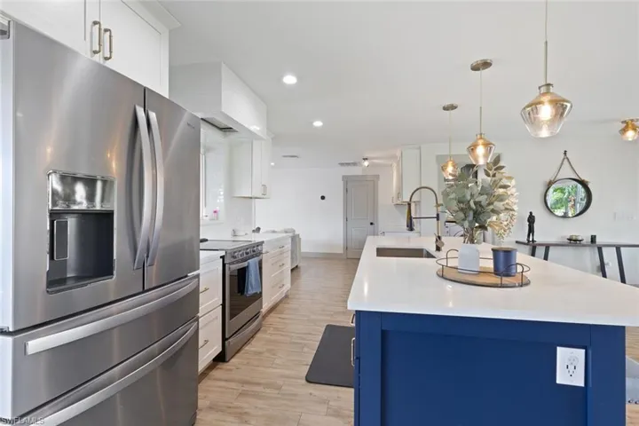 Kitchen with appliances with stainless steel finishes, light wood finished floors, light countertops, white cabinets, and recessed lighting