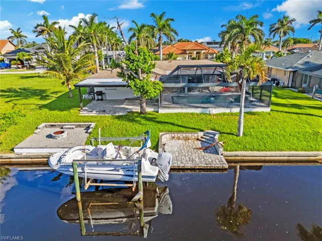 Dock area featuring a patio area, boat lift, a water view, and a yard