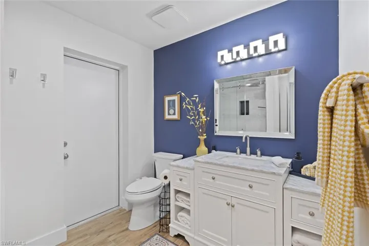 Full bathroom featuring vanity, wood finished floors, and a stall shower