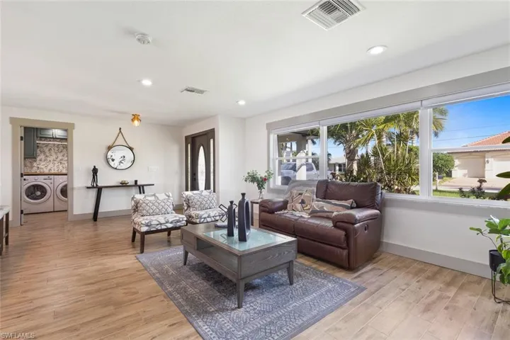 Living area with washer and clothes dryer, light wood finished floors, and recessed lighting