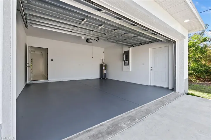 Garage featuring a garage door opener, electric panel, and electric water heater