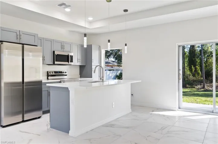 Kitchen featuring a kitchen island with sink, appliances with stainless steel finishes, sink, and pendant lighting